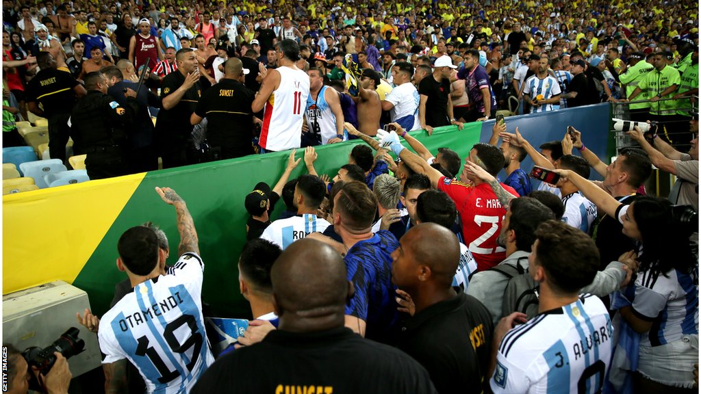 Igrači Argentine pored tribina pokušavaju da smire stvari dok se policija sukobljava sa navijačima