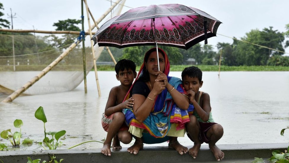 Женщина и дети укрываются на высоте во время наводнения, которое произошло в Калгачии в районе Барпета штата Ассам, Индия, 12 июля 2019 года.