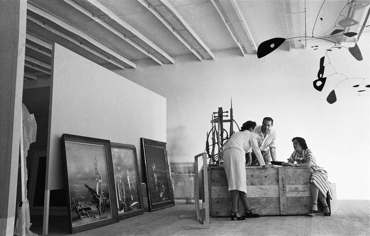 Montagem da I Bienal do Museu de Arte Moderna de São Paulo, esplanada do Trianon, avenida Paulista, 1951. René d'Harnoncourt, diretor do moma, entre duas pessoas não identificadas; à esquerda, pinturas de Yves Tanguy: Divisibilidade indefinida (1942), Os transparentes (1951) e Lentamente para o norte (1951); à direita, móbile Ogunquit (1946), de Alexander Calder