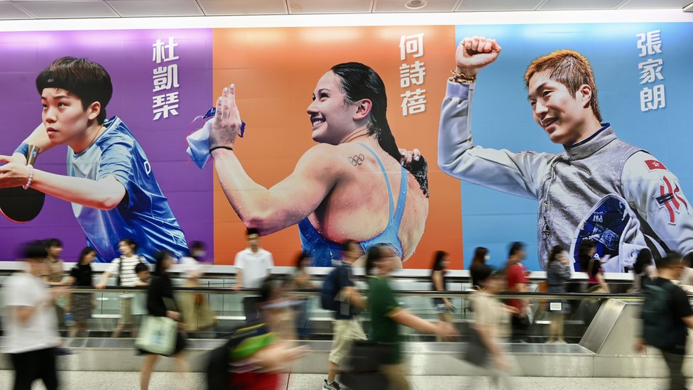 HONG KONG, CHINA - JULY 31: People walk past a poster of foil fencer Cheung Ka Long, swimmer Siobhan Bernadette Haughey and table tennis player Doo Hoi Kem at a subway station on July 31, 2024 in Hong Kong, China. (Photo by Li Zhihua/China News Service/VCG via Getty Images)