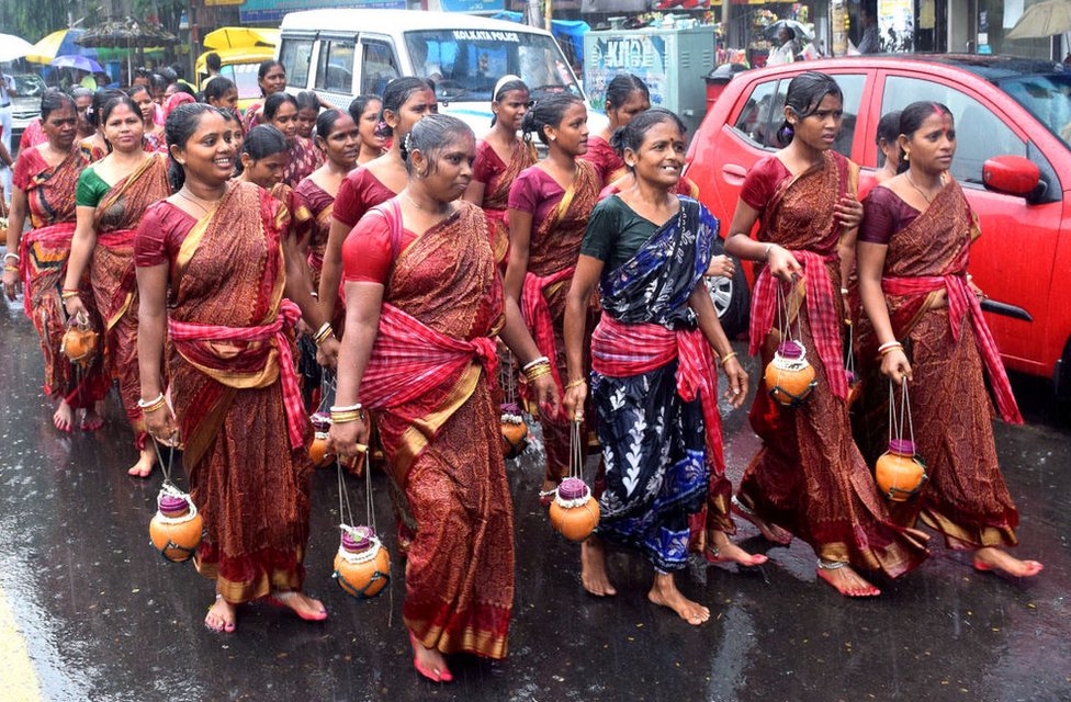 Несмотря на проливной дождь, мужчины и женщины канварии идут маршем к храму Шивы в Калькутте, чтобы предложить святую воду из Ганга.