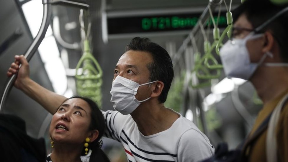 Мужчина в защитной маске (С) едет на поезде в Сингапуре