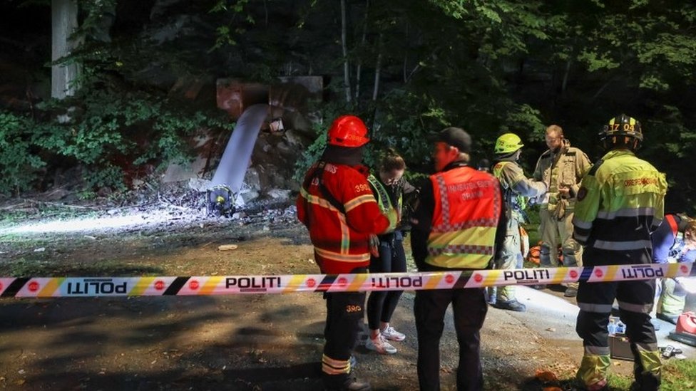 Emergency personnel are seen at the site where seven people have been found unconscious and sent to hospital after they were probably poisoned with carbon monoxide at a party in a bunker in Oslo