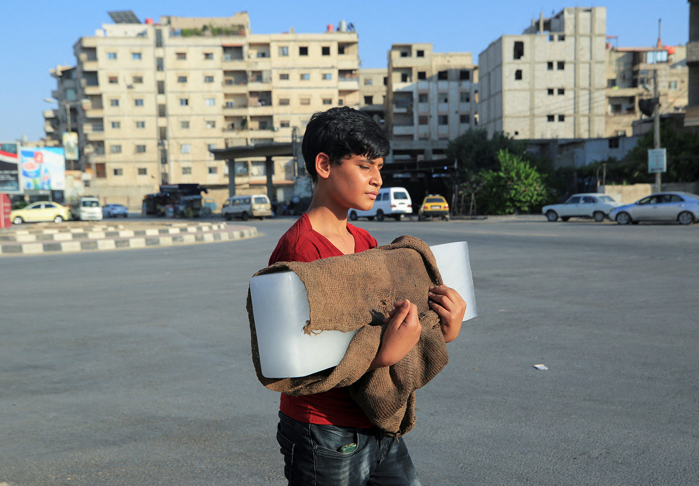 ​​A boy carries an ice block he walks along a street in in Damascus during a heatwave in Syria - 17 July 2023