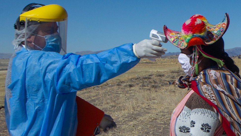 Doctor tomando la temperatura a una mujer indígena en Perú.