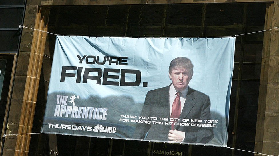 Вывеска с рекламой телешоу «Ученик» висит на Башнях Трампа 15 апреля 2004 г. в Нью-Йорке
