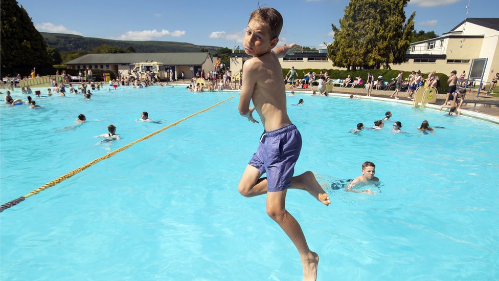 A boy jumps into the water at Ilkley outdoor pool and lido in west Yorkshire