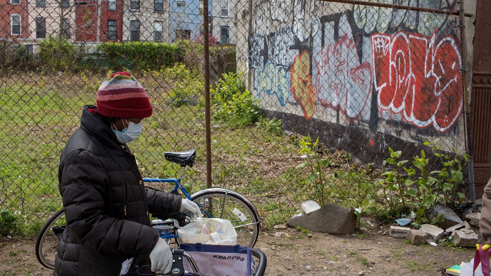 Mujer caminando en un barrio con grafiti en la pared de un terreno baldío en Estados Unidos
