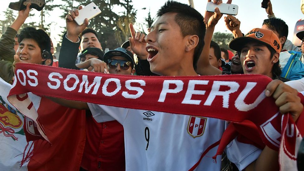 Fanáticos de fútbol con una bufanda que lee: "Todos somos Perú".
