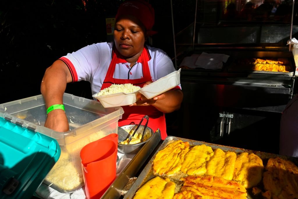 Una mujer prepara una bandeja con plátano maduro que sirve en una feria de comida callejera en Medellín, Colombia.