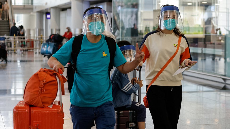 一位男士與家人步出香港國際機場抵達大堂後舉起勝利手勢（26/9/2022）