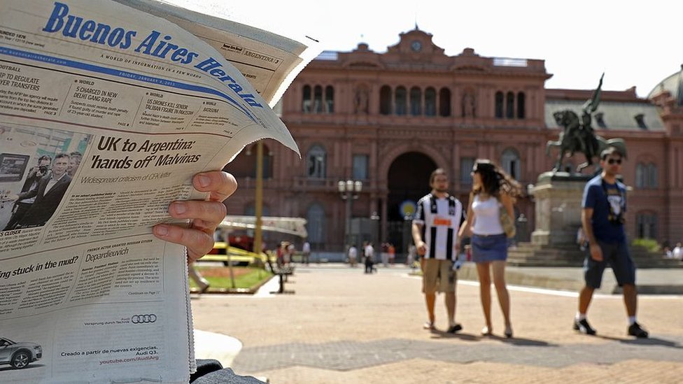 Persona leyendo el Buenos Aires Herald frente a la Casa Rosada