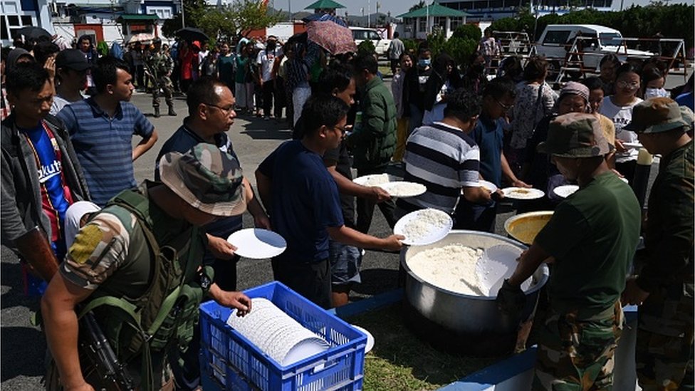 يصطف الناس في طابور لتوزيع الطعام من قبل الجيش الهندي في مطار إيمفال في 7 مايو/أيار 2023، أثناء فرارهم من العنف العرقي الذي ضرب ولاية مانيبور شمال شرق الهند