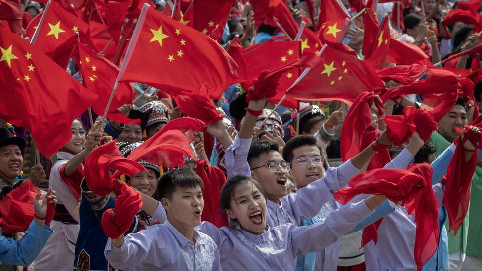 Китайские участники размахивают национальным флагом на параде, посвященном 70-летию основания Китайской Народной Республики в 1949 году,