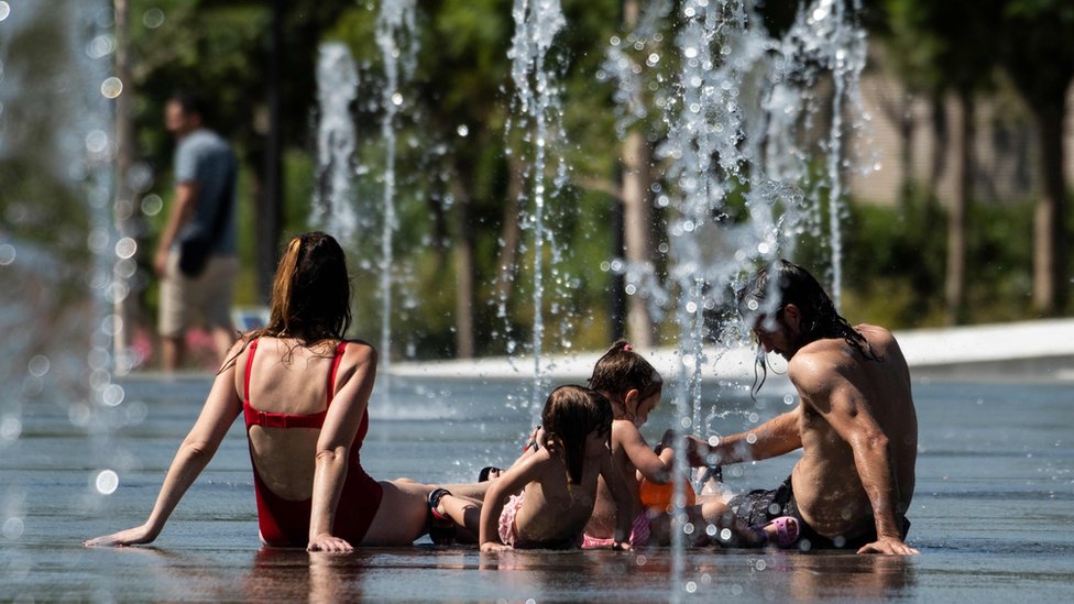 Люди охлаждаются в фонтанах в Центральном парке во время сильной жары в Валенсии