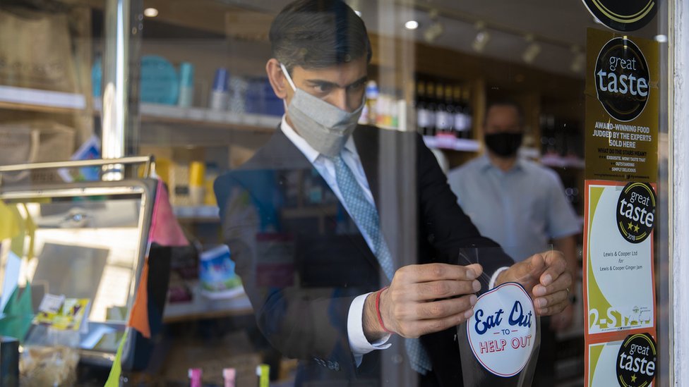 Канцлер Риши Сунак наклеивает наклейку «Перекусить, чтобы помочь» в окне