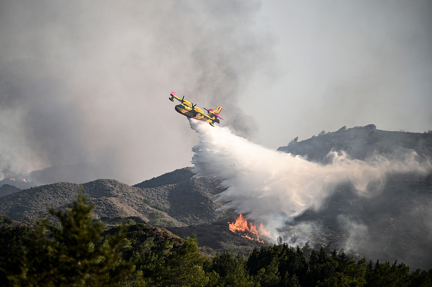 ​​A fire fighting aircraft drops water over a wildfire close to village of Vati in the southern part of the Greek island of Rhodes - 25 July 2023