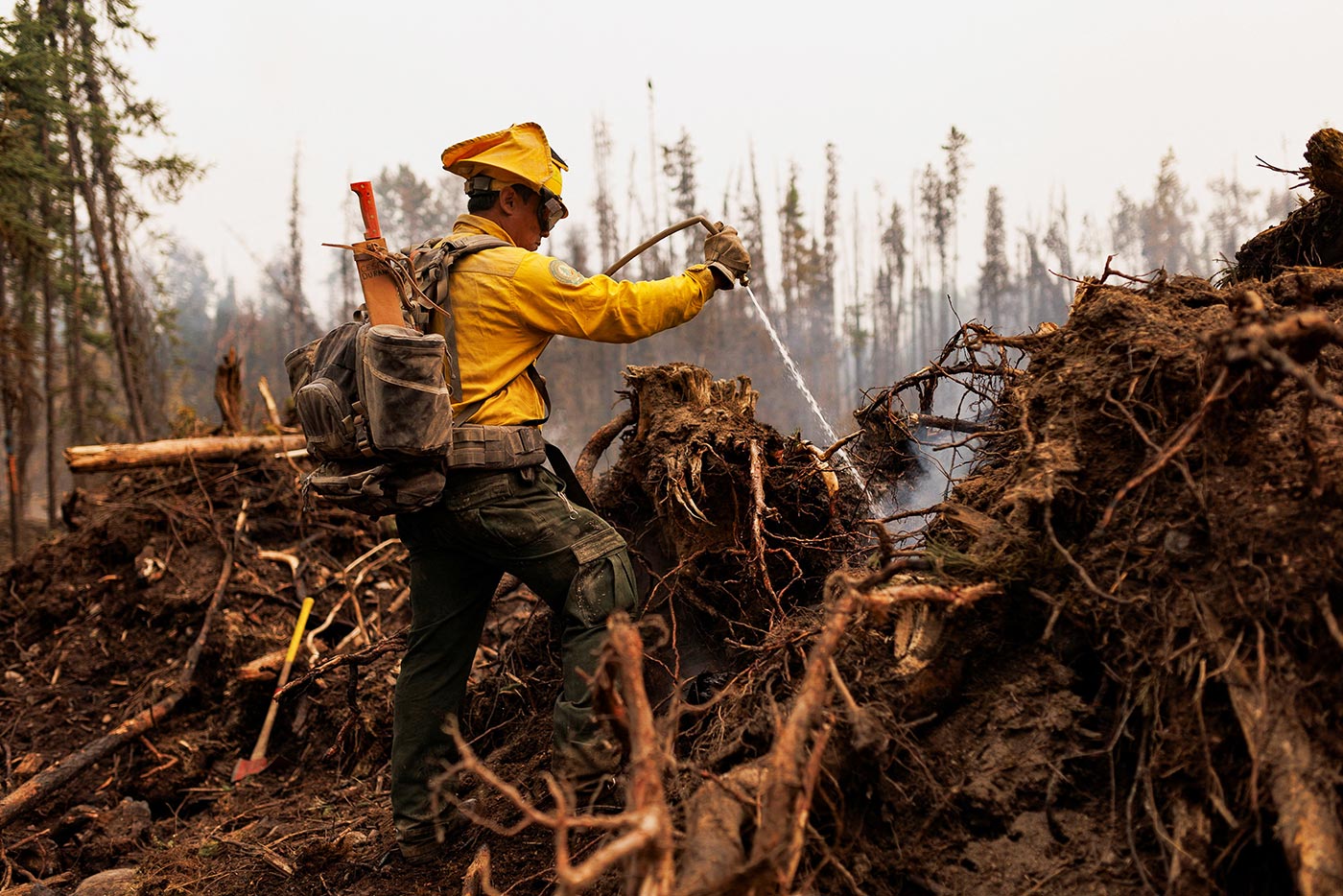 A firefighter from Mexico uses a hose to extinguish hotspots on a wildfire burning near Vanderhoof, British Columbia, Canada - 13 July 2023