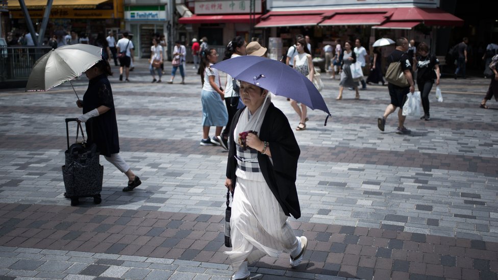 Žena nosi kišobran dok prelazi ulicu u Tokiju, 23. jul, 2018.