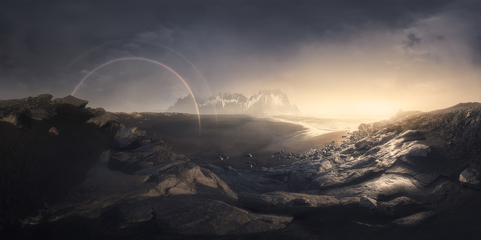 A mountain landscape view of a sunrise and a rainbow
