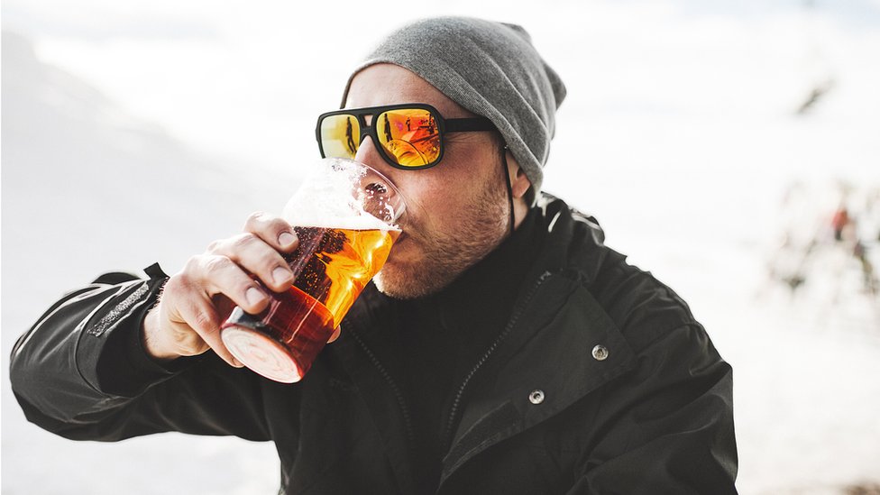 Hombre bebiendo cerveza en la nieve