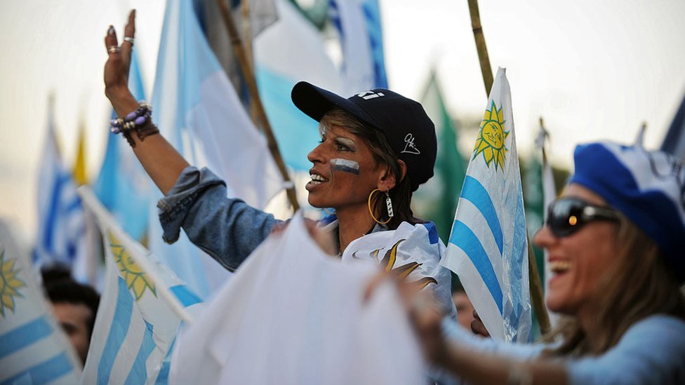 Mujer rodeada de banderas de Uruguay