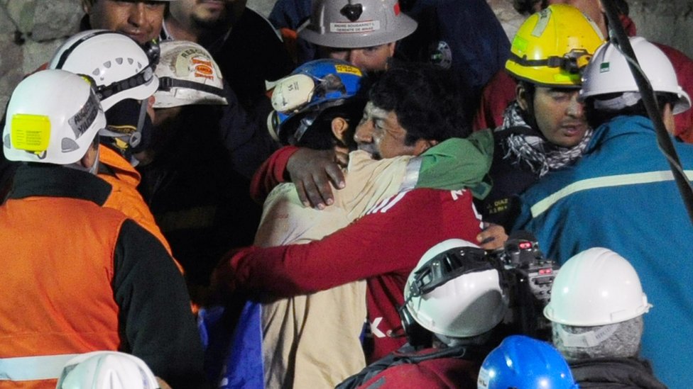 Чилийского шахтера Джимми Санчеса приветствует его отец после того, как его спасли из шахты Сан-Хосе