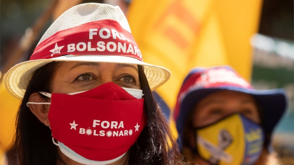 Mulher com máscara e chapéu que estampam símbolo do PT e frase 'Fora Bolsonaro'