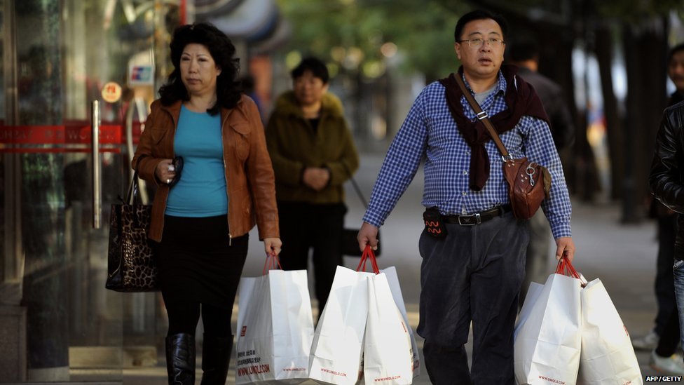 Китайская пара с сумками для покупок выходит из торгового центра в Пекине