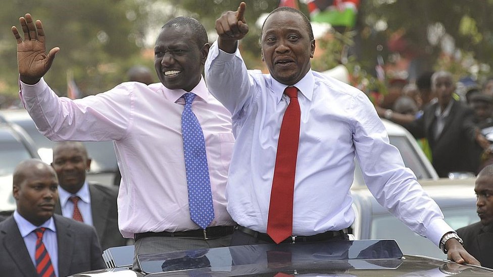 Kenya's president Uhuru Kenyatta (R) waves to the welcoming crowd flanked by deputy-president William Ruto on October 9, 2014 in Nairobi, a day after becoming the first sitting president to appear before the International Criminal Court on crimes against humanity charges