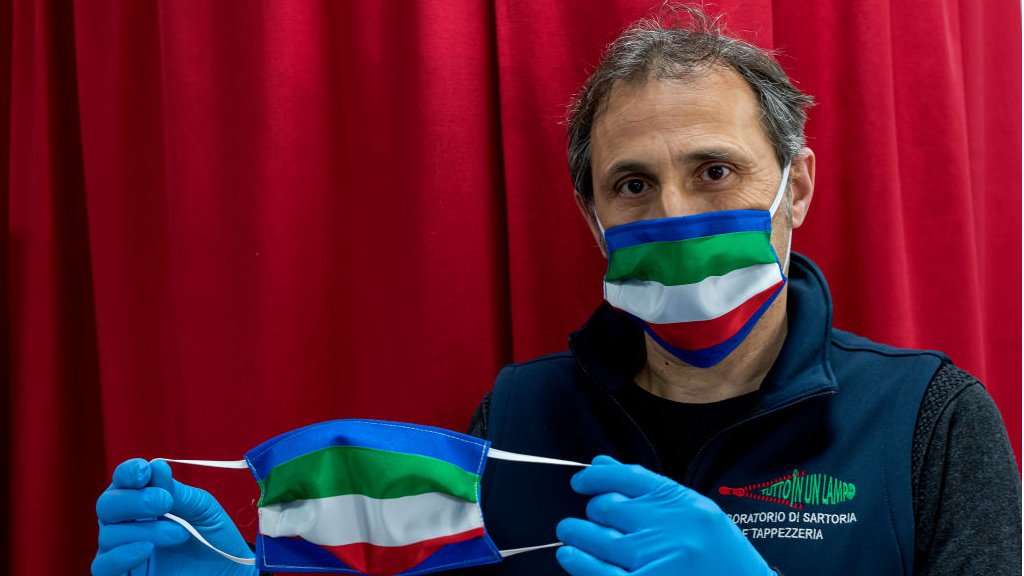 صاحب محل خياطة في ايطاليا يبرز كمامة تحمل علم البلاد