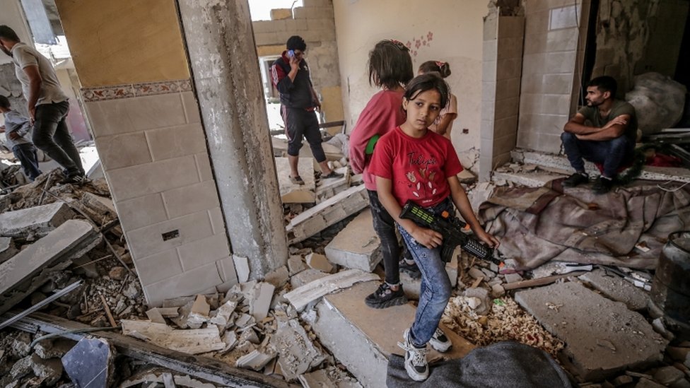 Chicas palestinas de pie entre los escombros de una casa
