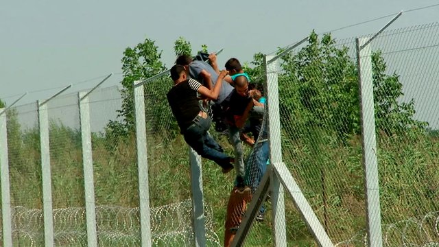 Afghan men breach the fence at Hungary's border
