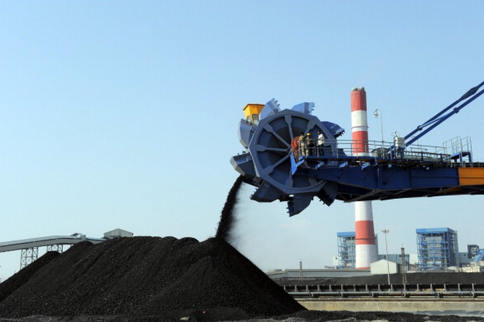 Workers use heavy machinery to sift through coal at the Adani Power company thermal power plant at Mundra some 400 kms from Ahmedabad on February 18, 2011.