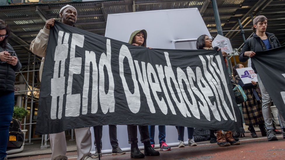 Manifestantes con un cartel que dice "Acaben con la sobredosis"
