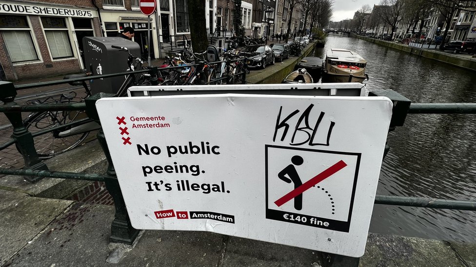 تظهر الصورة لافتة تحذر من التبول في الأماكن العامة
