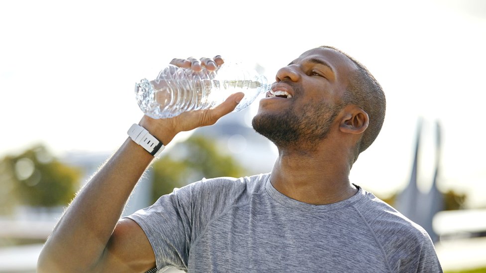 Hombre bebiendo botellas de agua.