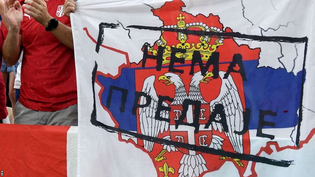 Serbia fans hold up a fllag depicting the outline of Kosovo filled with Serbia's flag, with words translated as 'no surrender'