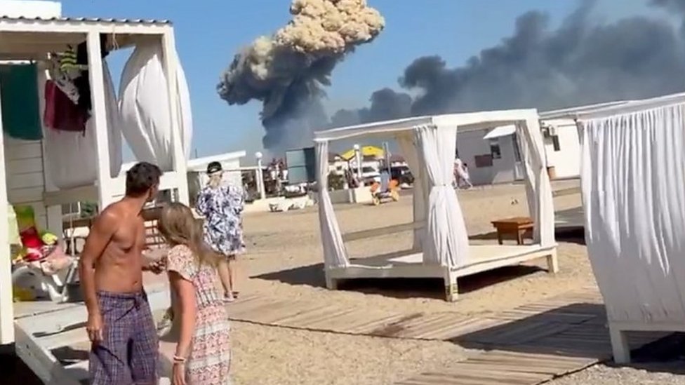 الناس على الشاطئ في شبه جزيرة القرم ، سحابة من الدخان في الخلفية