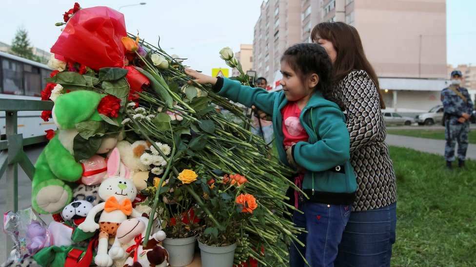 People lay flowers at a makeshift memorial for victims of a deadly shooting at School No 175 in Kazan, Russia, 11 May 2021