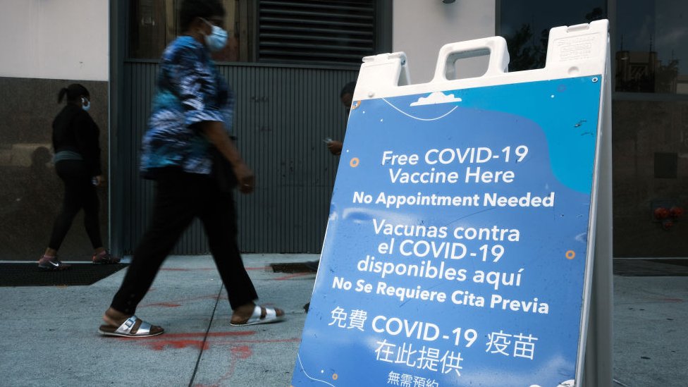 Una persona camina en Nueva York frente a una unidad móvil de vacunación.