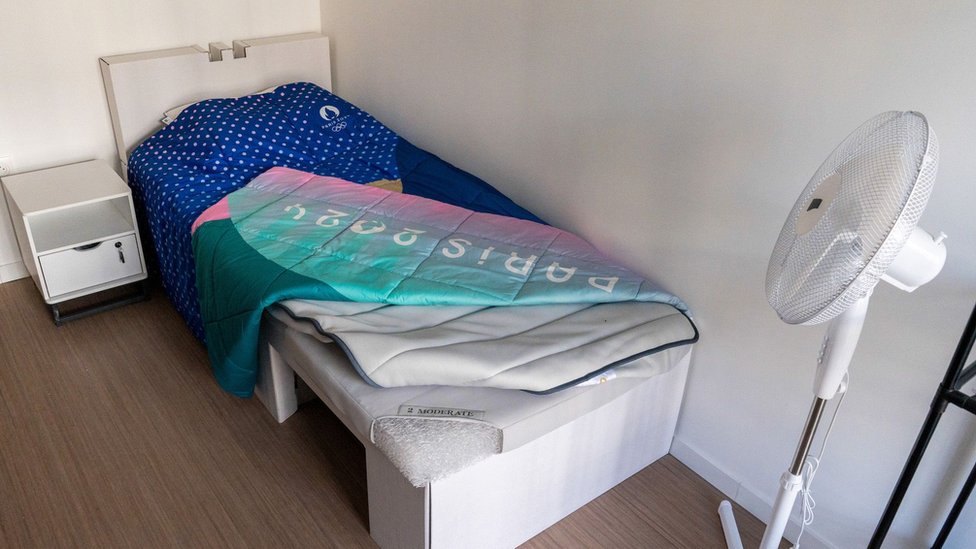 Kartonski krevet u jednoj od soba u Olimpijskom selu i pored njega ventilator