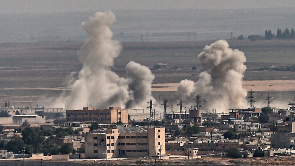 Дым поднимается над сирийским городом Рас-эль-Айн на снимке, сделанном с турецкой стороны границы в Джейланпинаре 11 октября 2019 г.