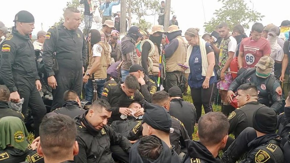 Police officers sit in a circle at a protest in Colombia