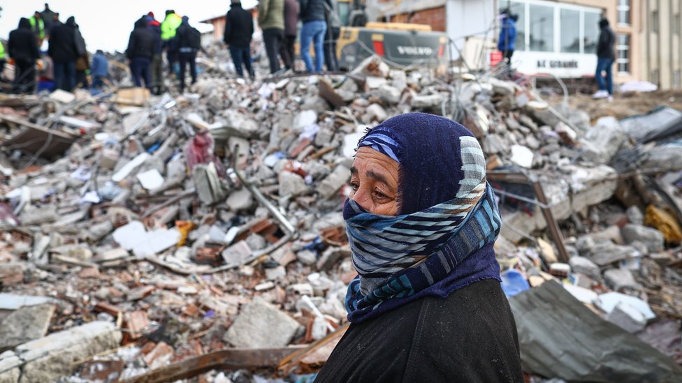 Una mujer observa a los servicios de rescate parados sobre los escombros en la provincia de Kahramanmaras, Turquía 8 de febrero 2023