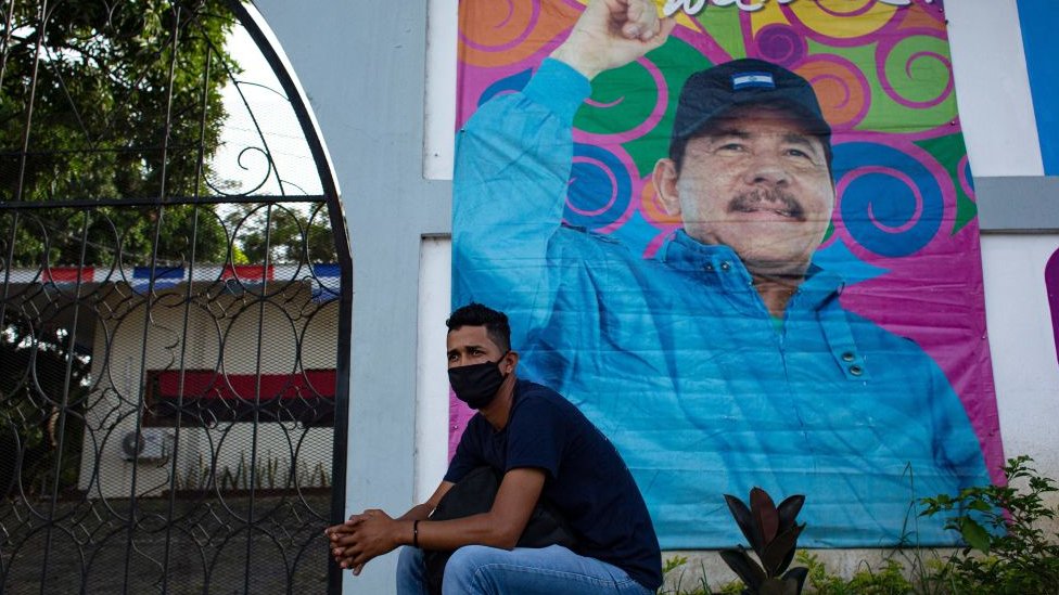 Hombre delante de una pancarta de la campaña de Ortega