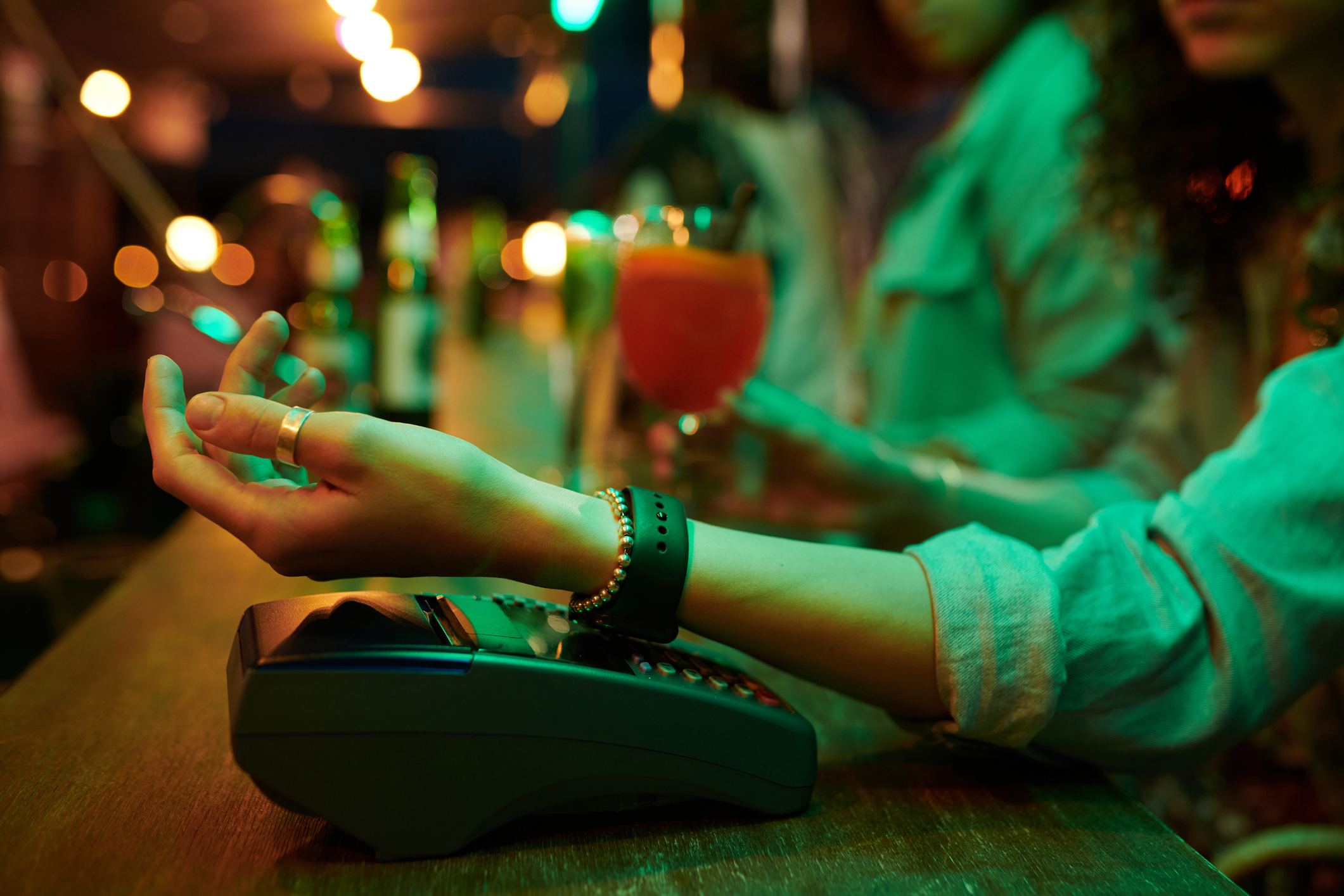 Mulher fazendo pagamento com smartwatch em balcão de bar