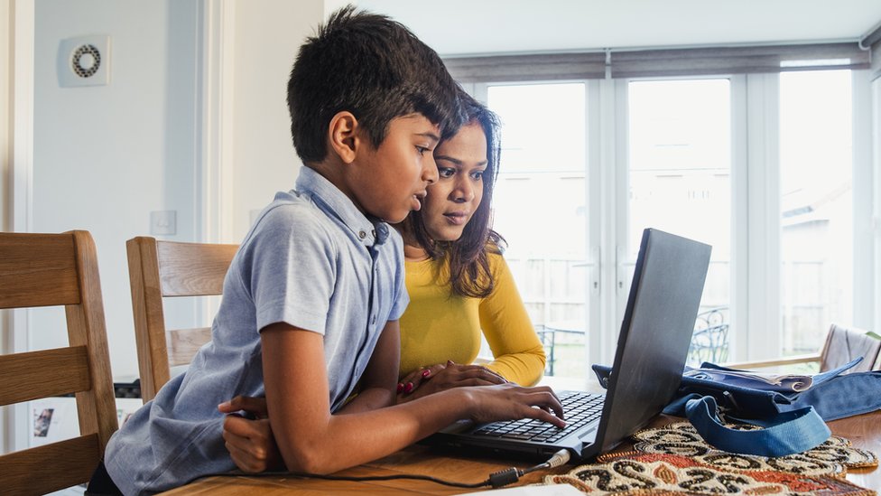 un niño y una niña usando una computadora.