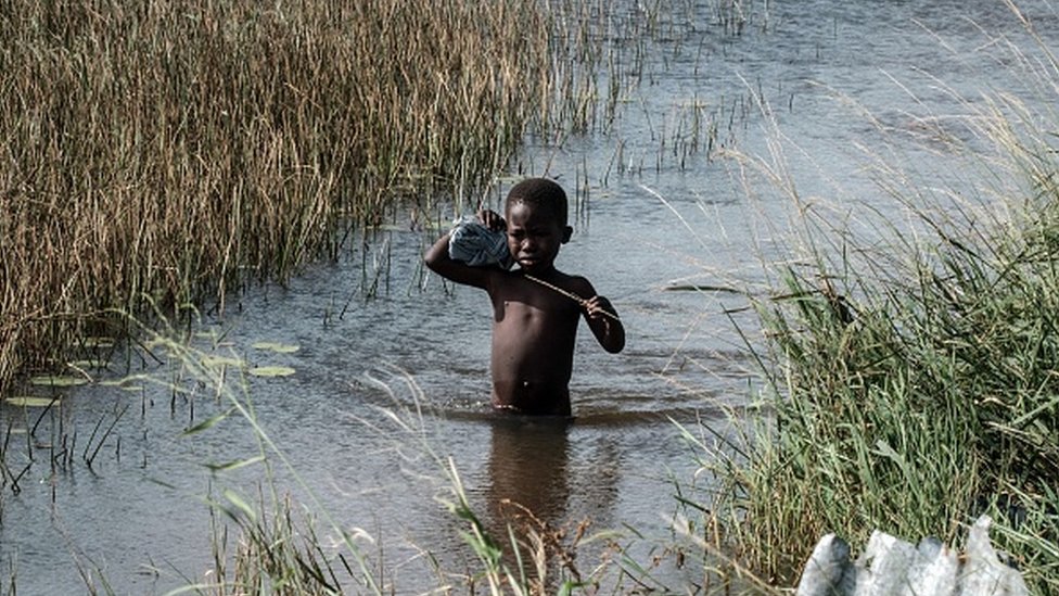 Niño cruzando un río.