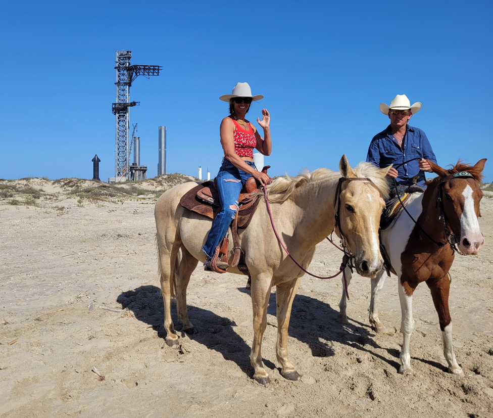 Gene Gore con su pareja y los caballos en Boca Chica Beach, con la plataforma de lanzamiento de SpaceX detrás.